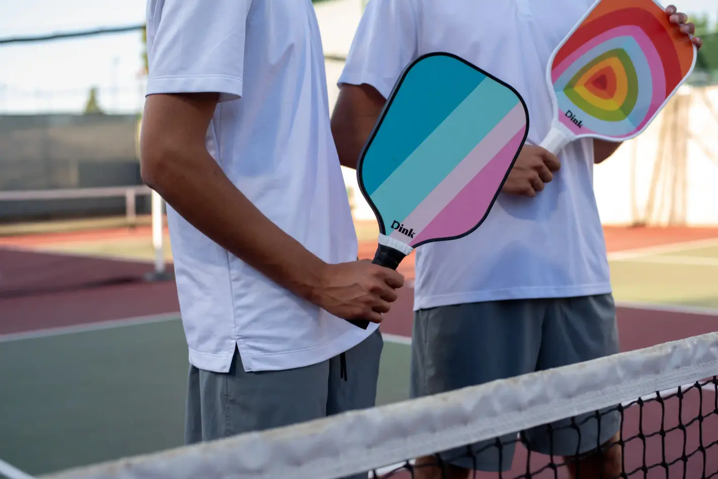 2 people holding Dink pickleball paddles in a pickleball field